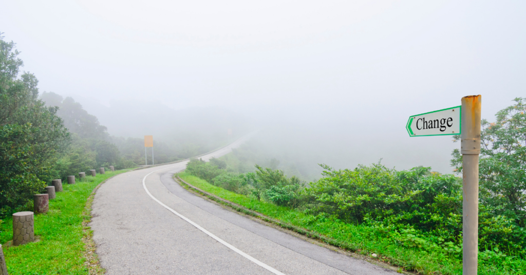 Une route qui s'enfonce dans le brouillard, avec un panneau « Change »